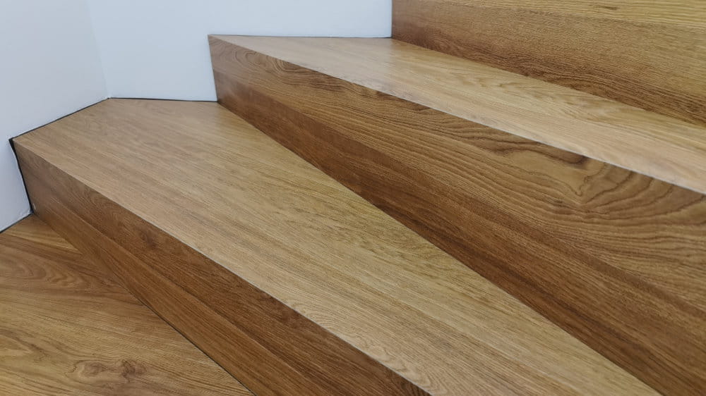 eine wunderschöne, mit Parkett verkleidete Treppe vor einer weißen Wand