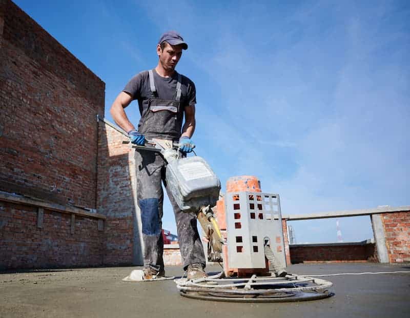 Bauarbeiter arbeitet Estrich ein mit einer Maschine