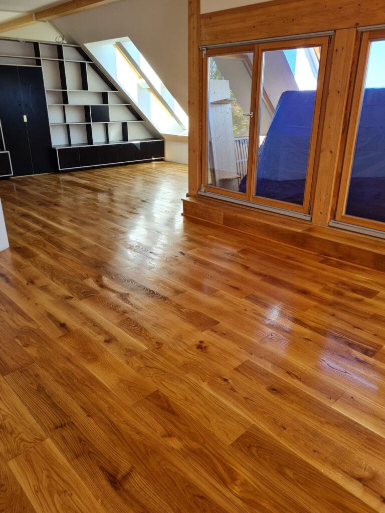 Parkett im Dachgeschoss mit Regal im Hintergrund und Fentsern