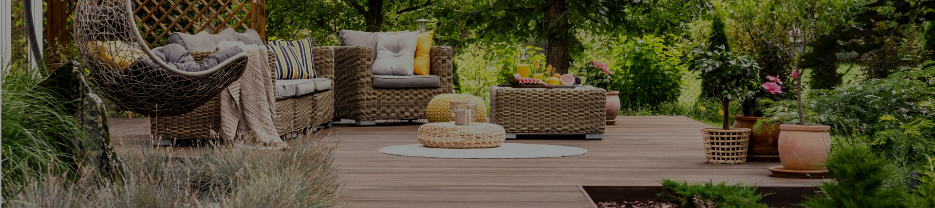 stilvolle Terrasse mit Rattanmöbeln in einem grünen Garten