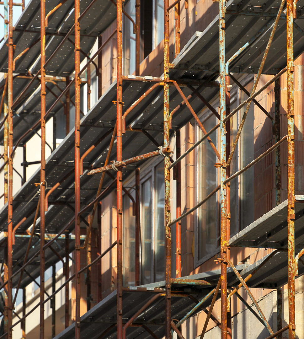 Rostiges Baugerüst an einer Fassade im Rohbauzustand bei einem Neubauprojekt.
