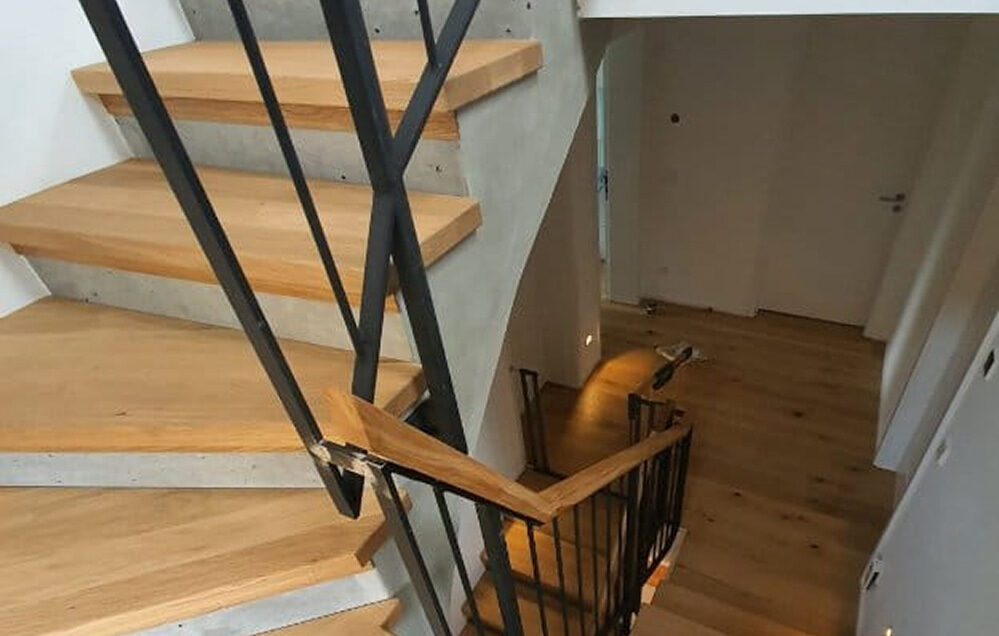 Beton-Holz-Treppe mit offenem Design und schwarzem Metallgeländer.