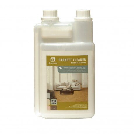 Weiße Plastikflasche von Scheucher Parkettreiniger mit einem Etikett, auf dem ein Wohnzimmer und ein Parkettboden abgebildet sind; die Flasche hat zwei Verschlüsse und ein Fassungsvermögen von 1 l.