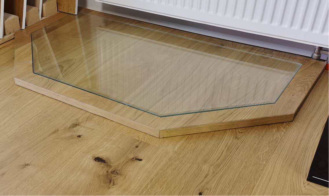 Sechseckige Funkenschutzplatte aus Glas auf Parkettboden – Domke Parkett GmbH Berlin, funktionaler und dezenter Schutz für den Kaminbereich