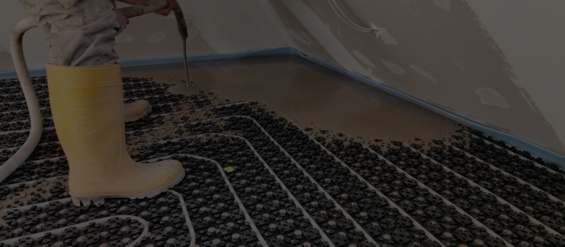 Einbau einer Fußbodenheizung mit Noppenplatte und frischem Fließestrich während einer energetischen Sanierung.