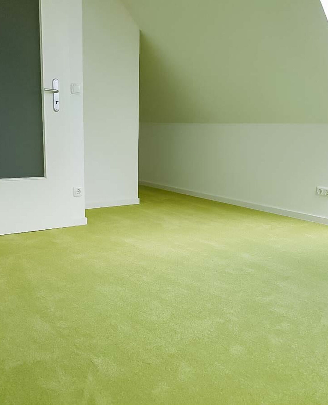 Grüner Velourteppich in einem hellen Dachgeschosszimmer mit Schräge und weißer Wandfarbe.