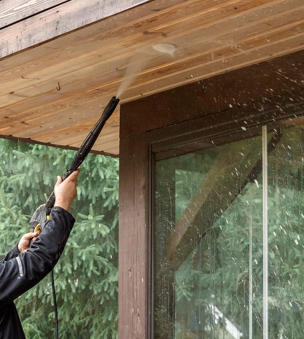 Reinigung einer Holzverkleidung an der Decke eines Hauses mit einem Hochdruckreiniger.