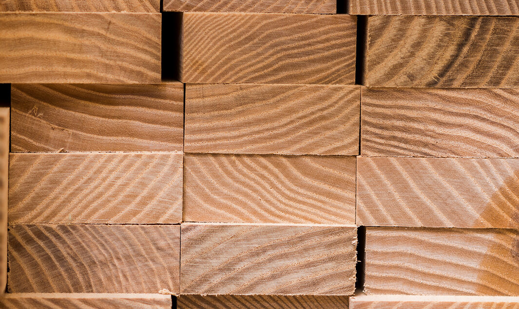 Gestapelte Holzbohlen mit gut sichtbarer Maserung – symbolisiert die sichere Lagerung und zuverlässige Verfügbarkeit von Holzmaterialien trotz angespannter Marktsituation.