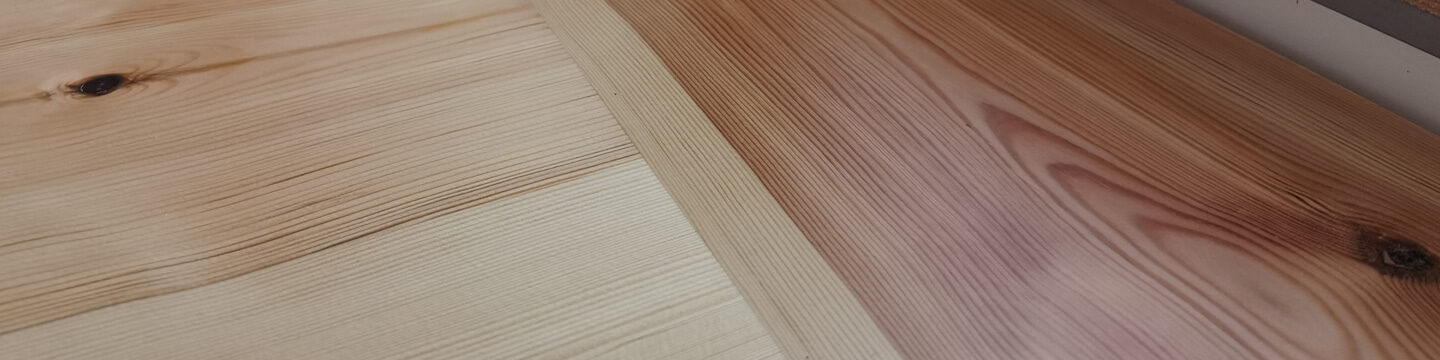 Detailaufnahme von zwei nebeneinanderliegenden Holzdielen mit deutlich sichtbarer Maserung und Farbunterschieden.