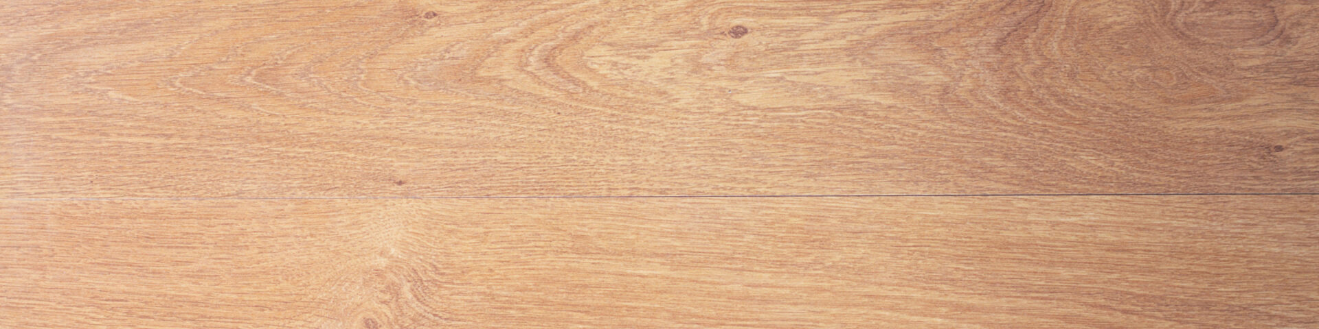 Zwei graue Laminatdielen mit sichtbarer Holzstruktur, auf denen ein Maßband liegt – Symbol für präzise Planung beim Bodenverlegen.
