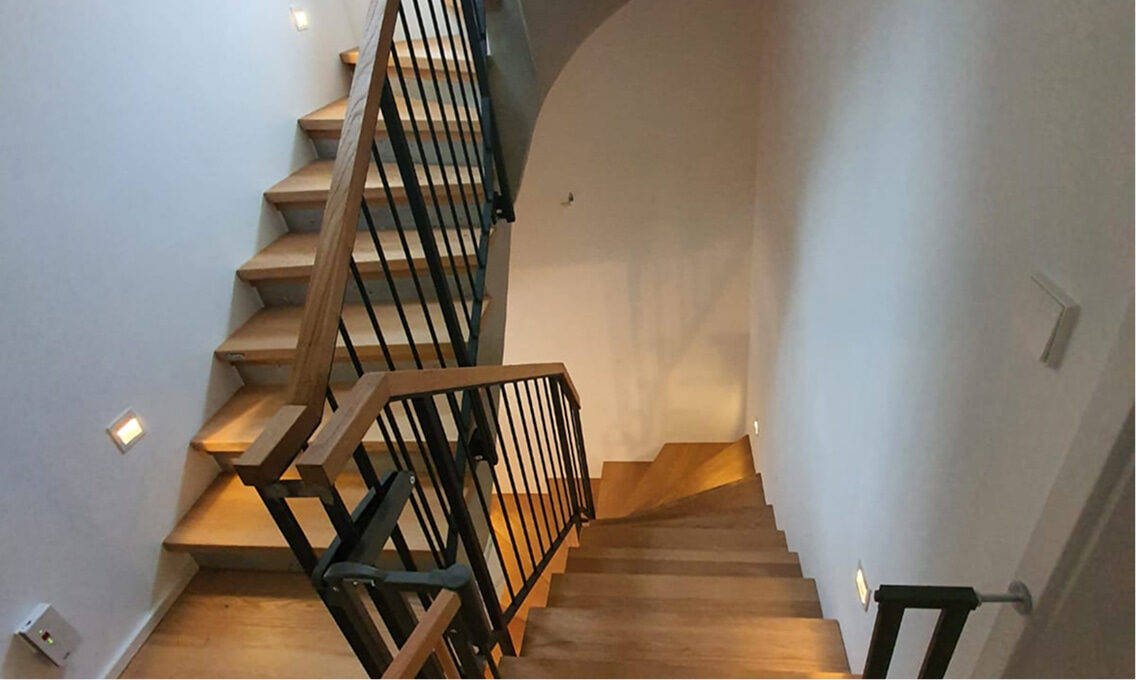 holztreppe mit metallgelaender und wandbeleuchtung