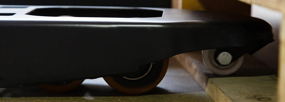Nahaufnahme eines stabilen Hubwagens mit Rollen unter einer Palette – steht sinnbildlich für den sicheren und flexiblen Transport von Parkettmaterial im Lager von Domke Parkett GmbH.