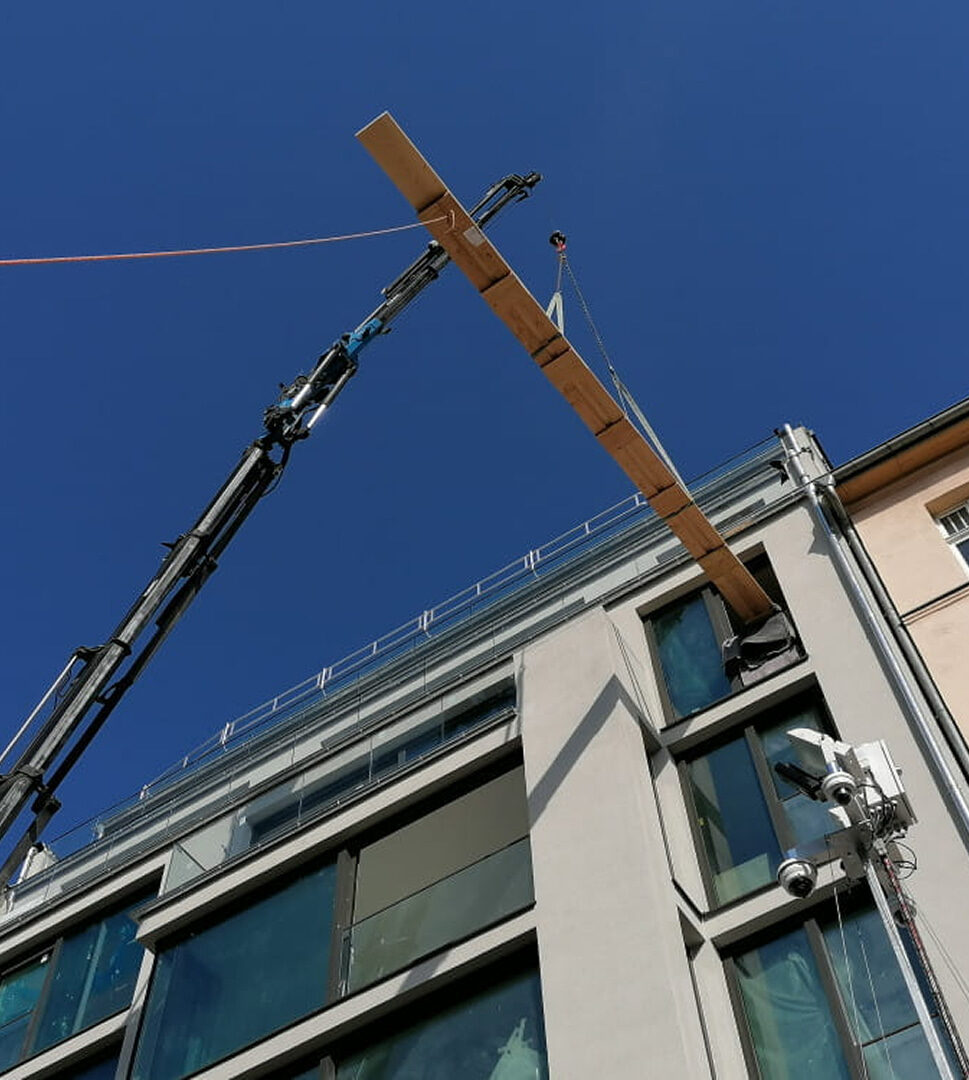 Lieferung raumlanger Massivholzdielen per Kran durch Fenster eines Altbaus.