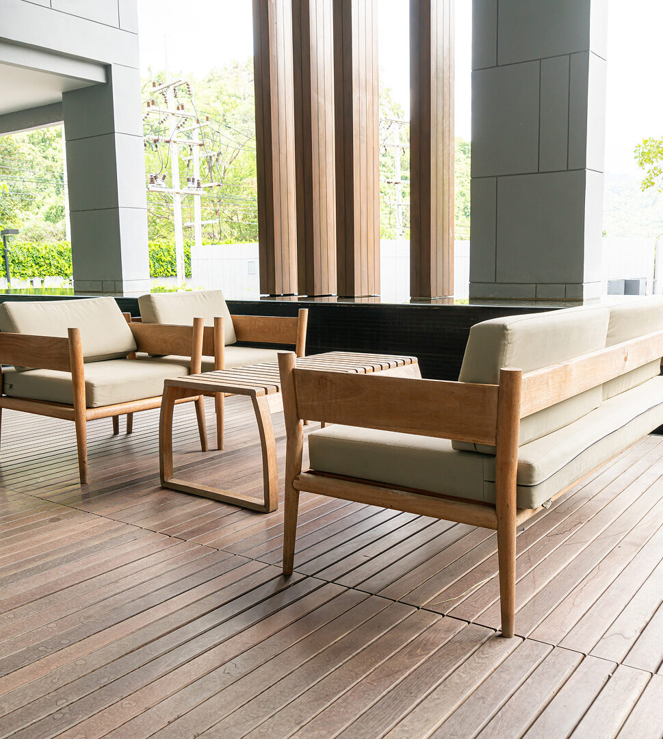 Moderne Terrasse mit hellbraunem Holzboden und minimalistischen Holzmöbeln im überdachten Bereich.