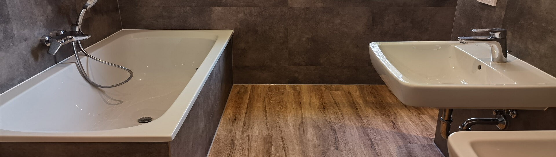 modernes Badezimmer mit Badewanne und Waschbecken auf Holzoptikboden.
