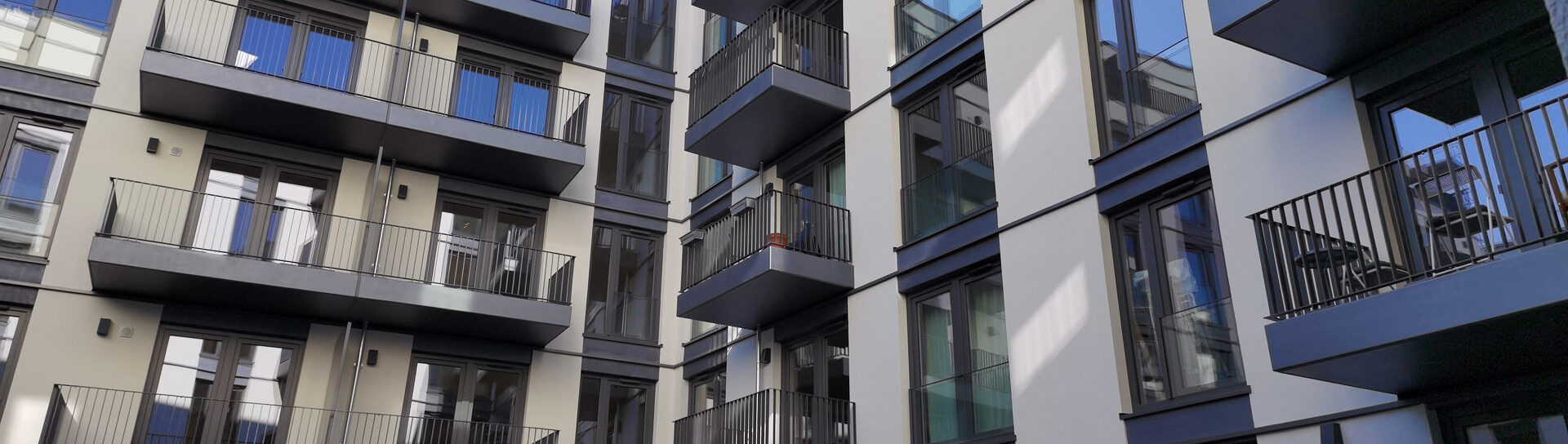 Moderne Wohn- und Gewerbeeinheiten mit mehreren Balkonen und großen Fensterflächen in einem Mehrfamilienhaus.