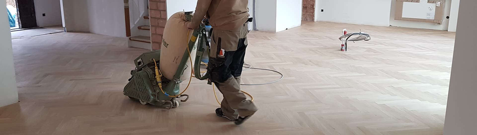 Facharbeiter der Domke Parkett GmbH Berlin schleift großflächigen Parkettboden mit professioneller Schleifmaschine – präzise Bodensanierung für ein perfektes Ergebnis