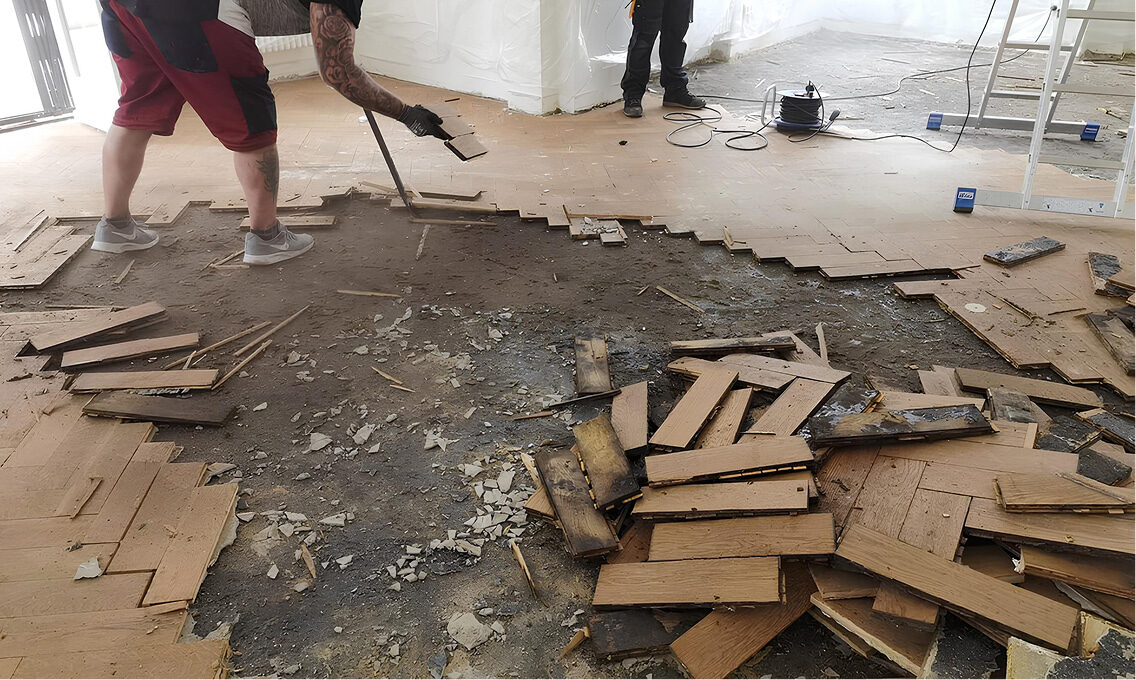 Entfernung eines alten Parkettbodens durch Handarbeit mit Brecheisen in einem renovierungsbedürftigen Raum.