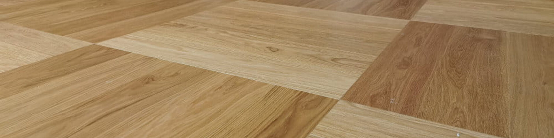 Würfelmuster aus hellem und mittlerem Eichenparkett in einem weißen Innenraum mit offener Tür.