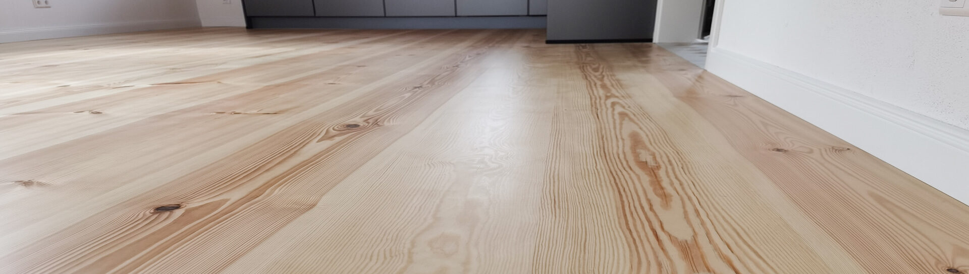 Raumlange Massivholzdielen aus Kiefer in modernem Neubau mit offener Küche.