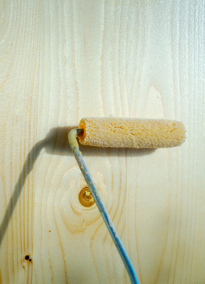 Farbrolle auf einer hellen Holzoberfläche – Symbolbild für Reinigungs- oder Pflegearbeiten an Parkettböden, bei denen spezielle Mittel gleichmäßig aufgetragen werden.