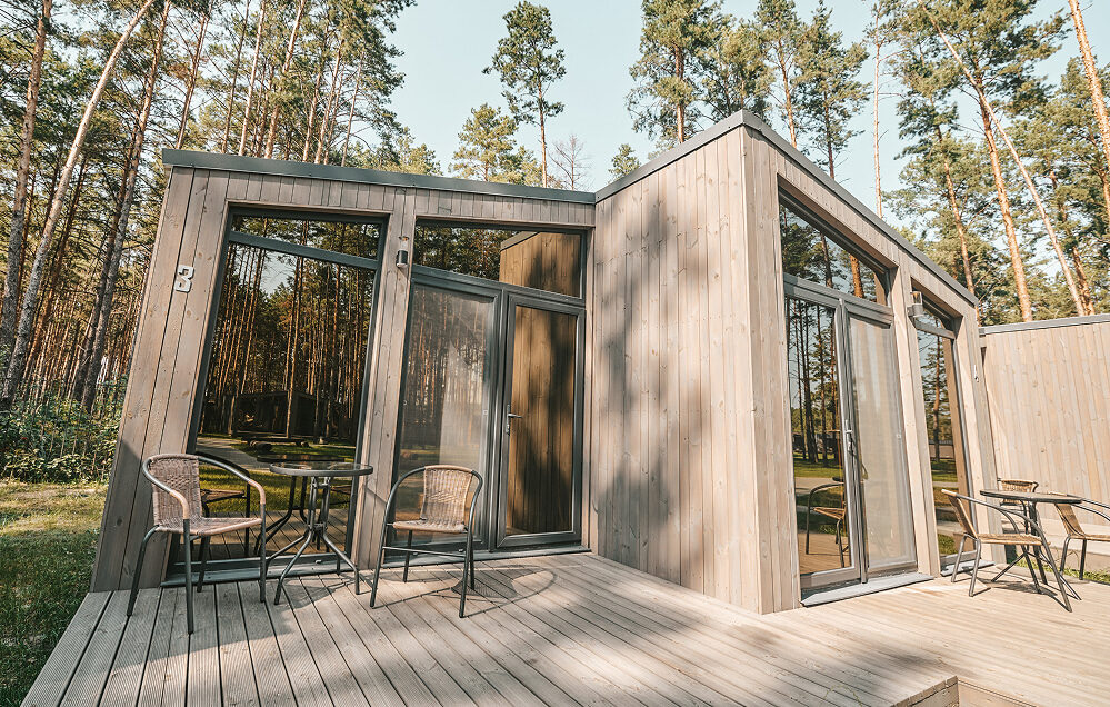 Saubere Holzterrasse vor einem modernen Ferienhaus im Wald.