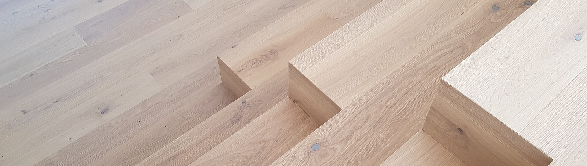 Moderne Holztreppe mit minimalistischer Stufenverkleidung aus hellem Eichenholz.
