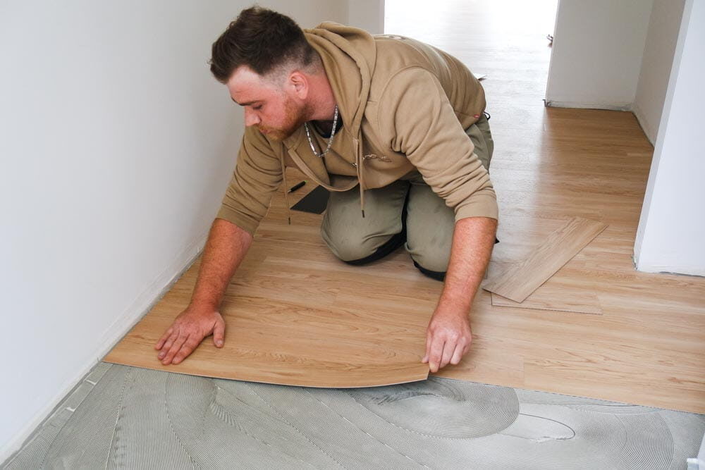 Ein Mitarbeiter von Domke Parkett verklebt Vinylstreifen fachgerecht auf dem Fußboden.