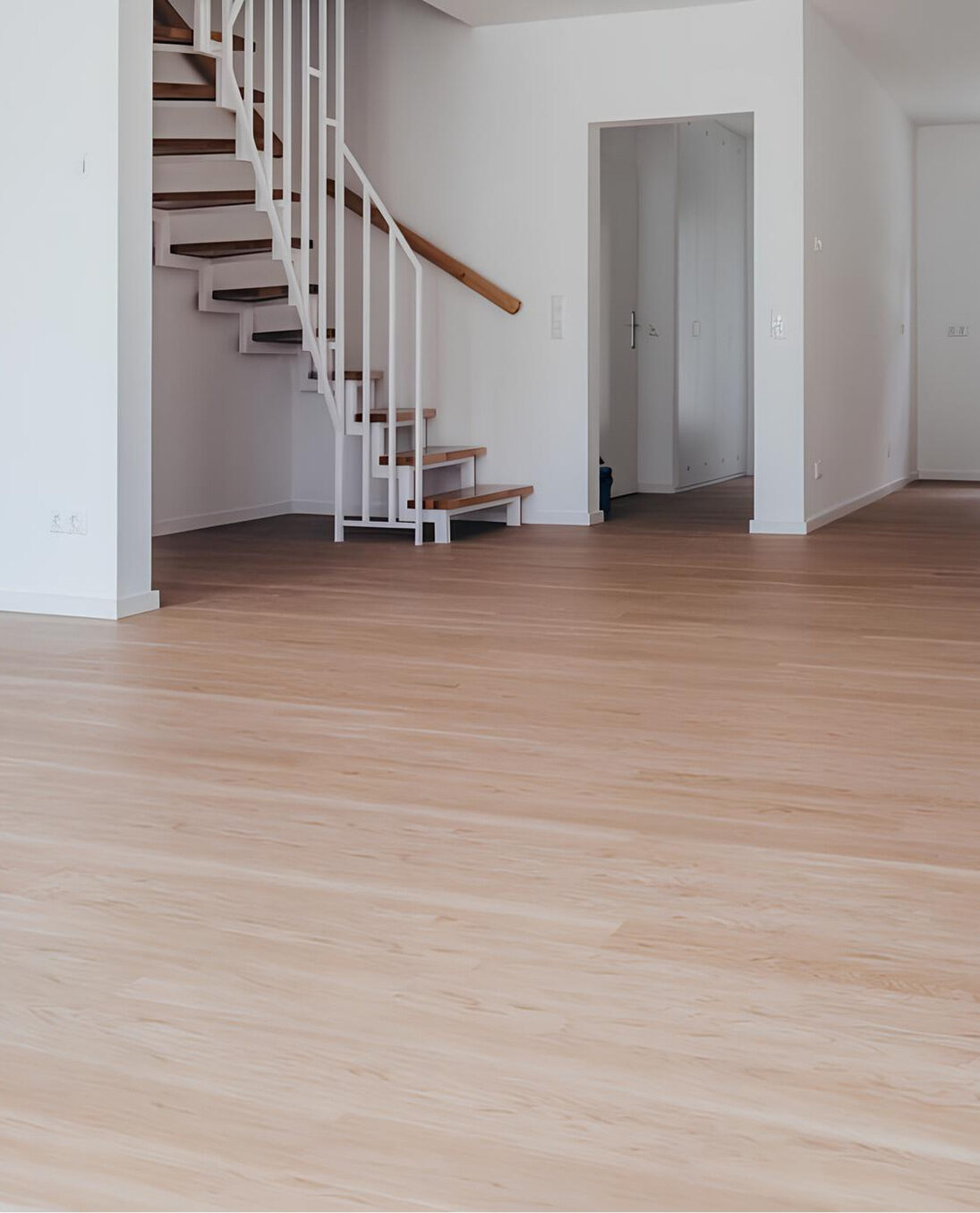 Vinylboden in natürlicher Eichenoptik verlegt in einem modernen Wohnraum mit offener Treppe und weißen Wänden.