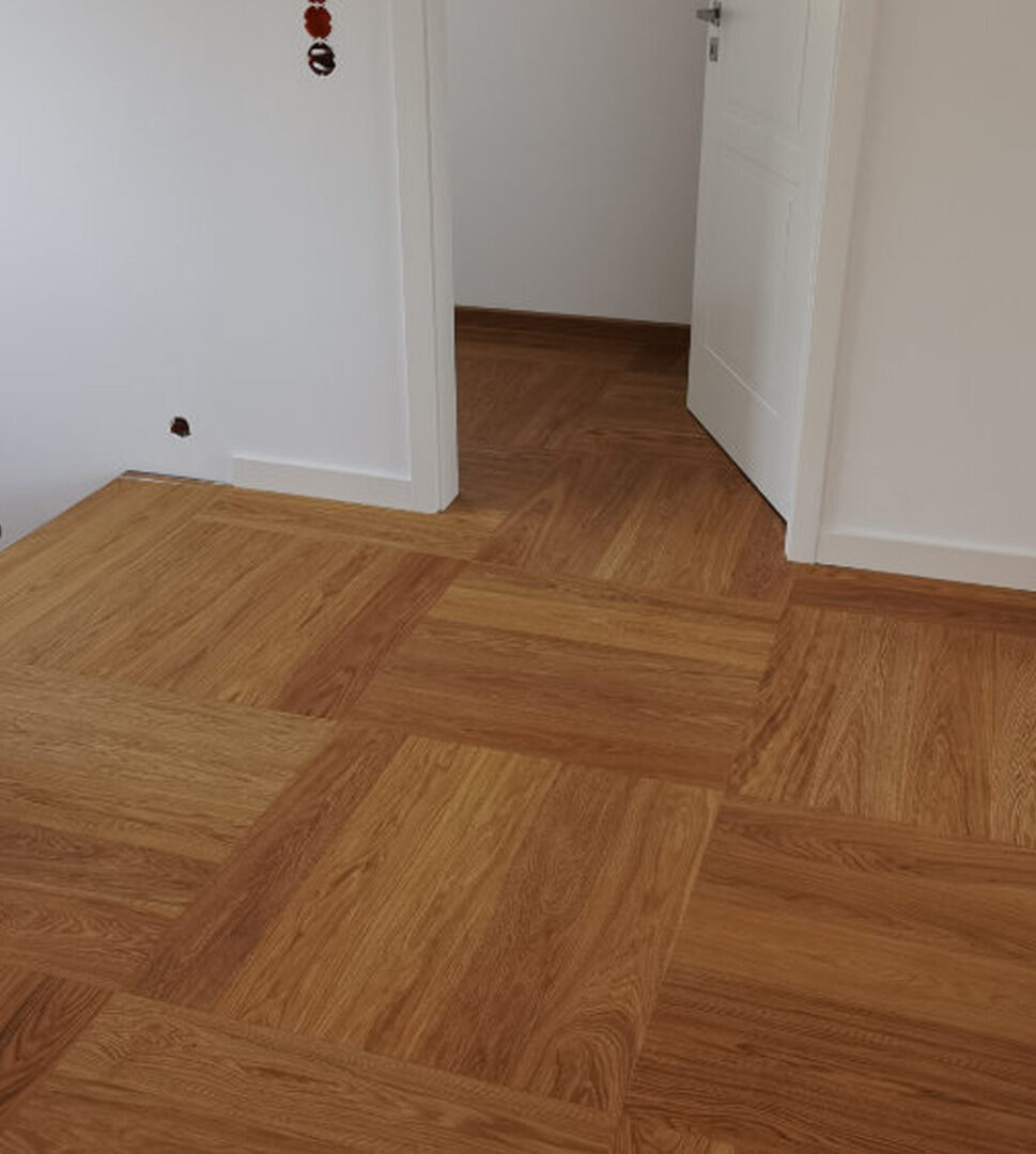 Würfelparkett in einem hellen Wohnbereich mit offener Tür und weißer Wandgestaltung.